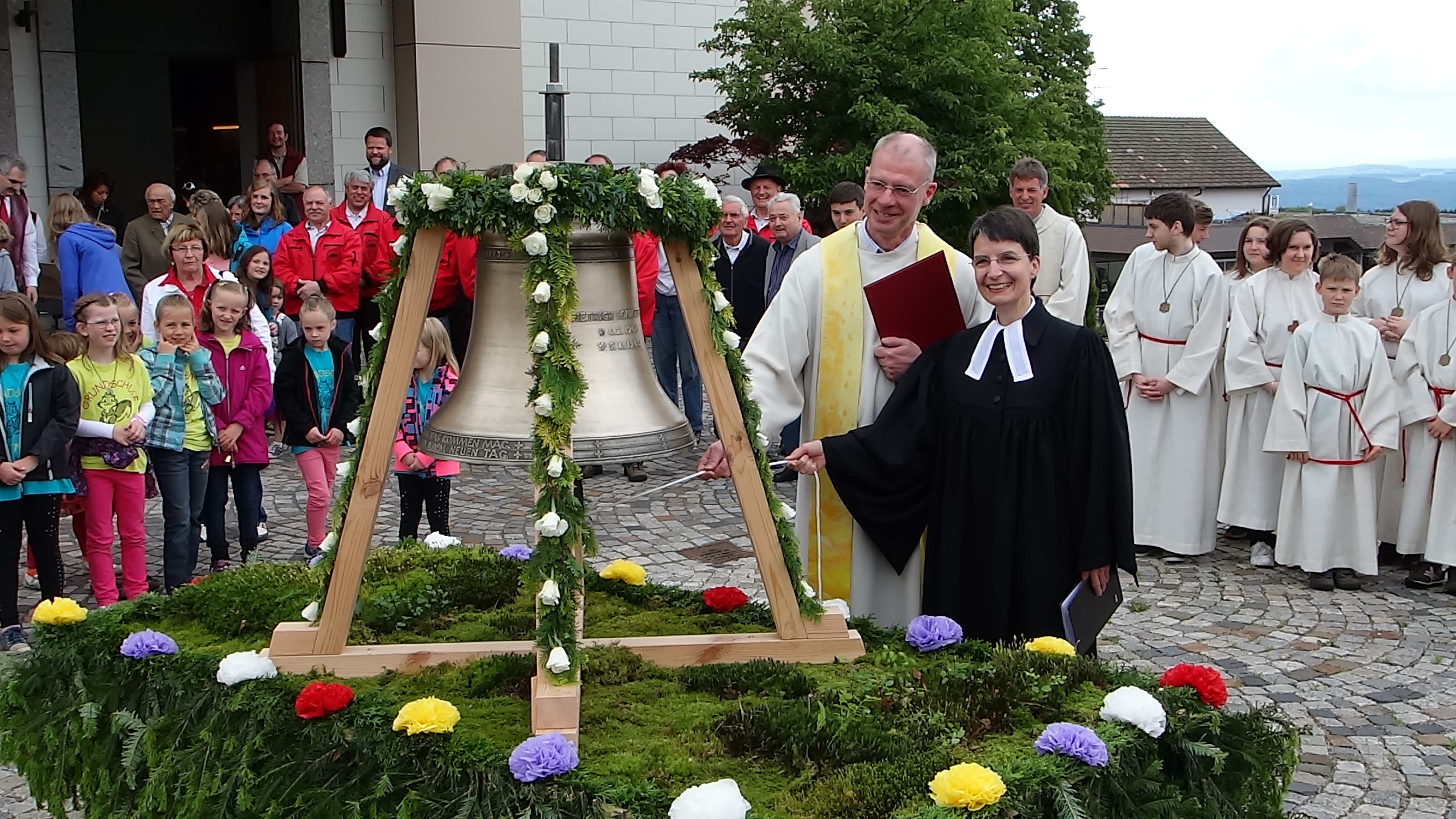Pfarrer Stahlberger und Pfarrerin Moser läuten gemeinsam die Dietrich-Bonhoeffer-Glocke auf dem Görwihler Kirchenvorplatz